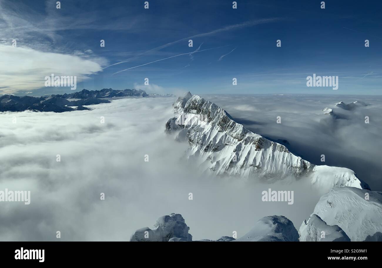 Vista dal Monte Titlis delle montagne che emergono dalle nuvole nelle Alpi, Svizzera. Foto Stock