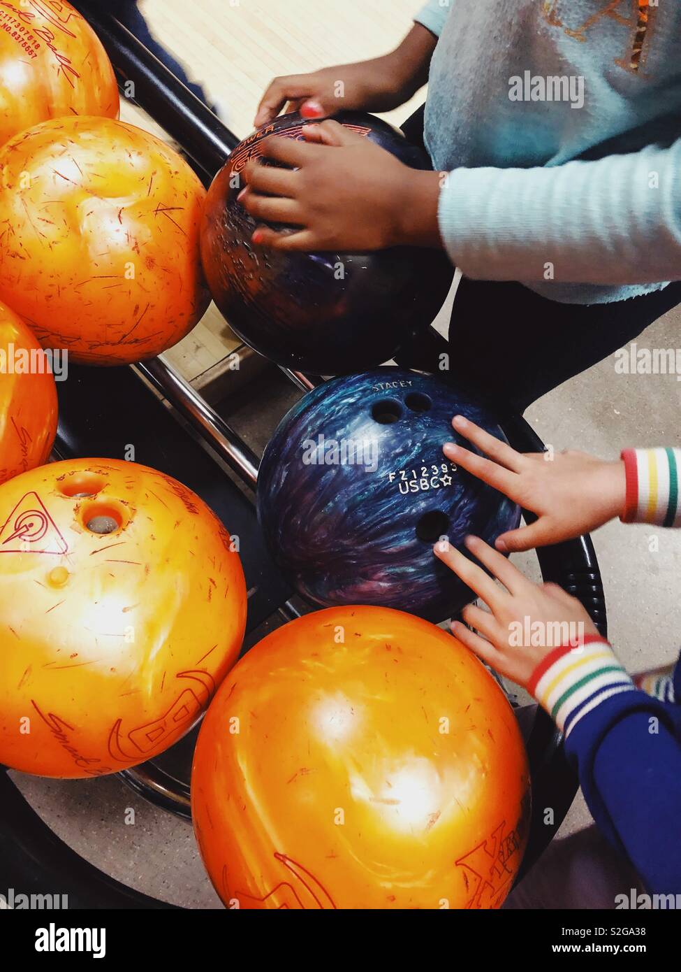 I bambini con le palle da bowling a una pista da bowling - Immagine stock catturata con smartphone