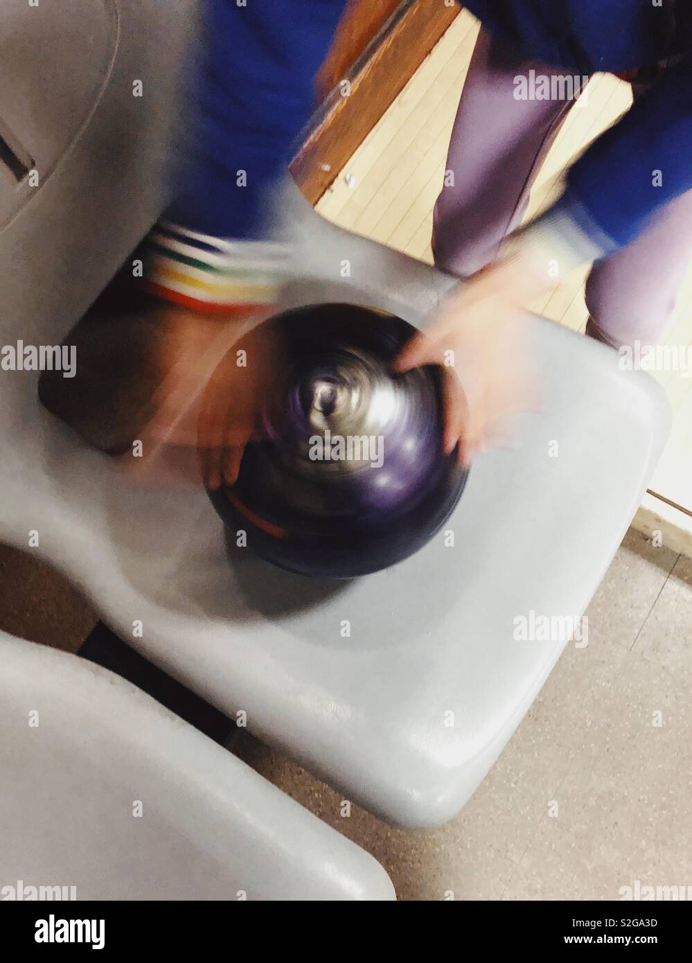 Un giovane bambino la filatura di una palla da bowling Foto Stock