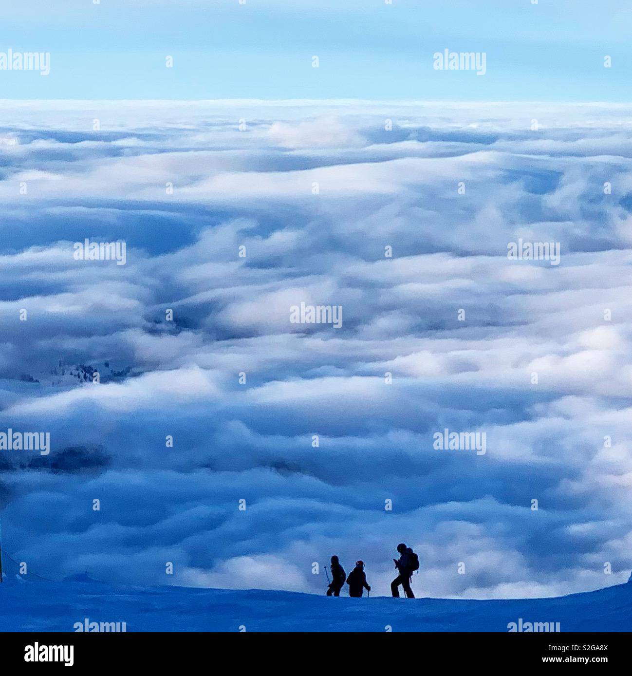 Tre gli sciatori che si affacciava su un mare di nuvole. Presa sul Monte Titlis Engelberg, Svizzera. Foto Stock