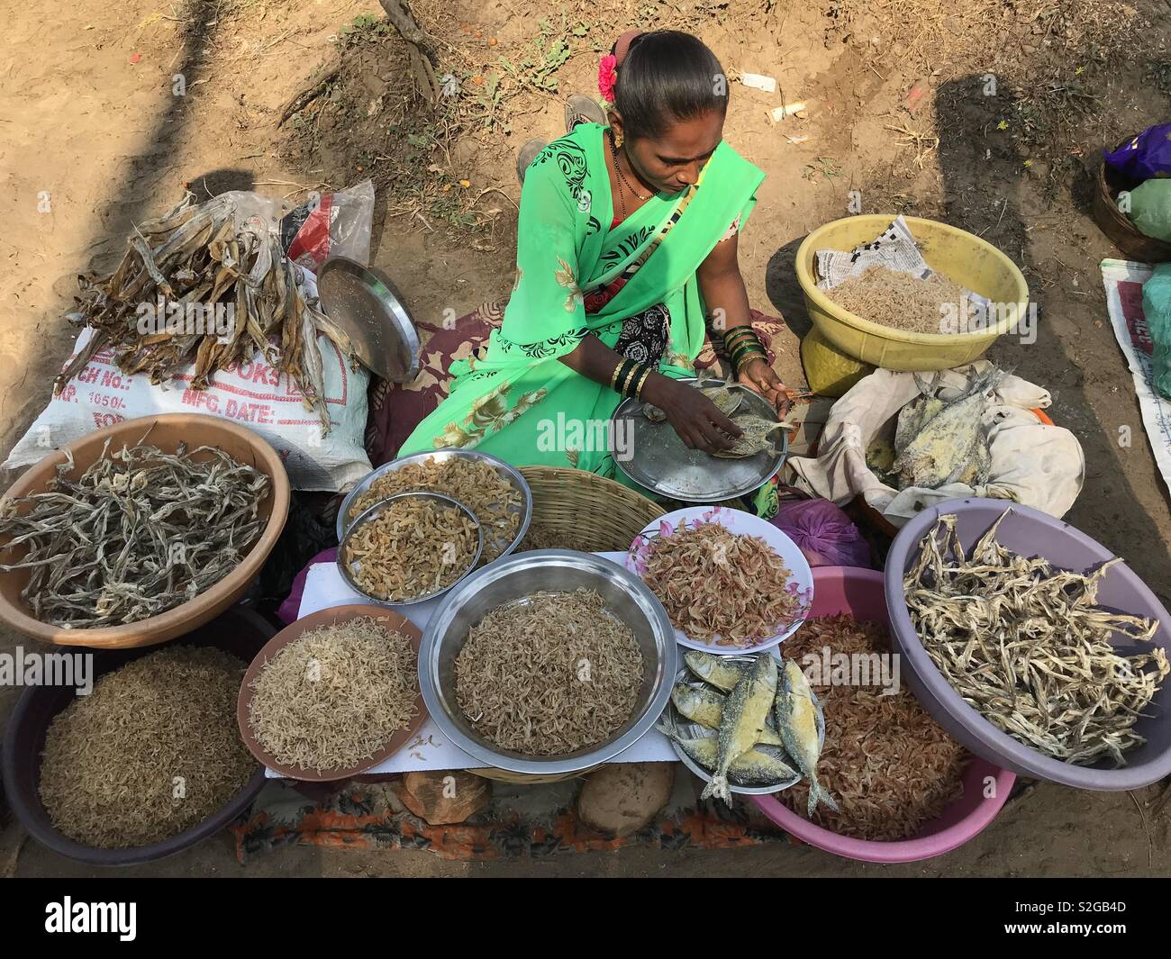 Una donna locale vende pesce secco sulla spiaggia di Alibaug, Mumbai, India. - Immagine stock catturata con smartphone