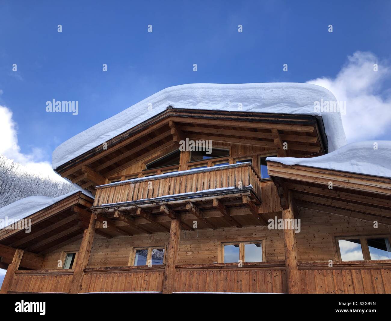 Neve profonda copre un tetto nelle alpi austriache su un luminoso soleggiato ma freddo giorno d'inverno. - Immagine stock catturata con smartphone
