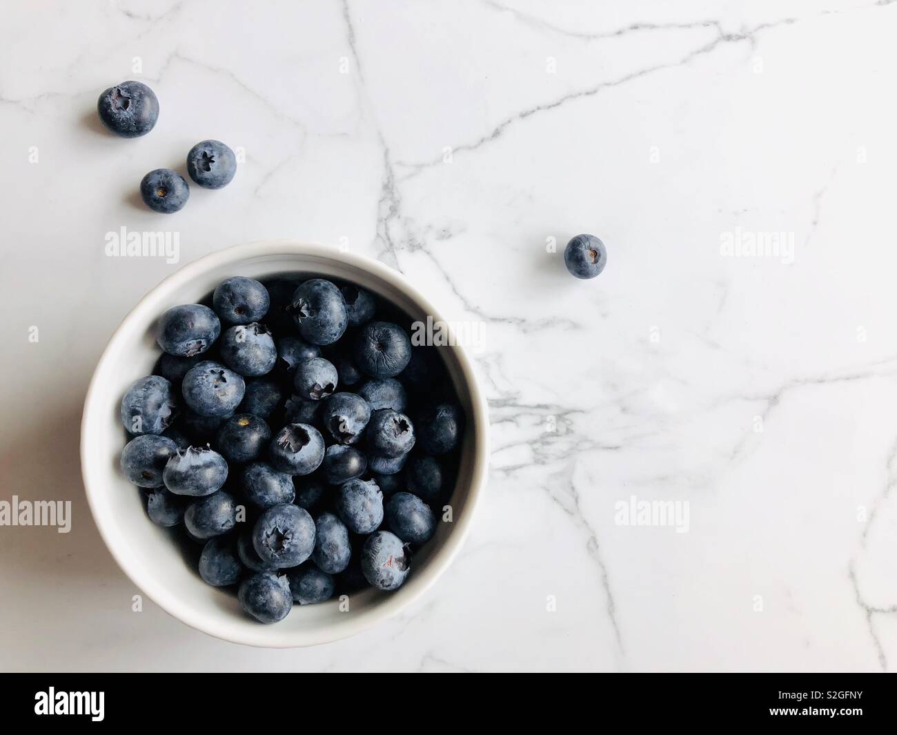 I mirtilli in una ciotola bianco su bianco superficie in granito con spazio di copia - Immagine stock catturata con smartphone