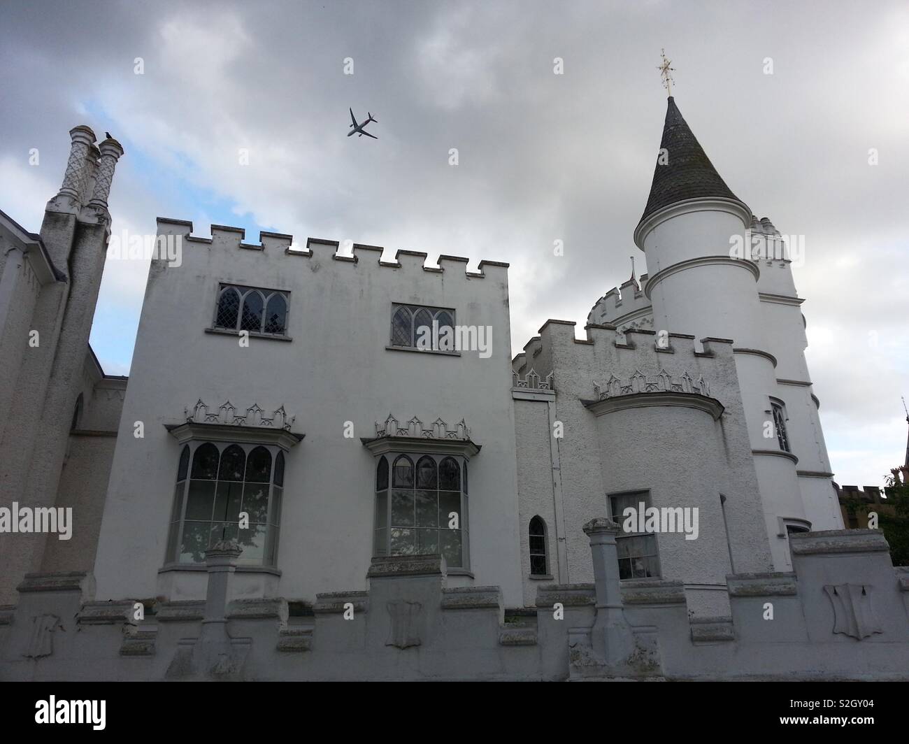 Vista frontale del Strawberry Hill House, Twickenham, una chiave Revival gotico edificio con un jumbo jet flying overhead. - Immagine stock catturata con smartphone