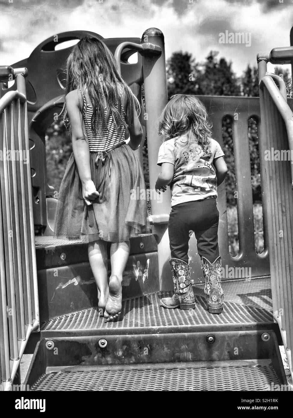 Retro di due sorelle camminando sul parco giochi in bianco e nero Foto Stock