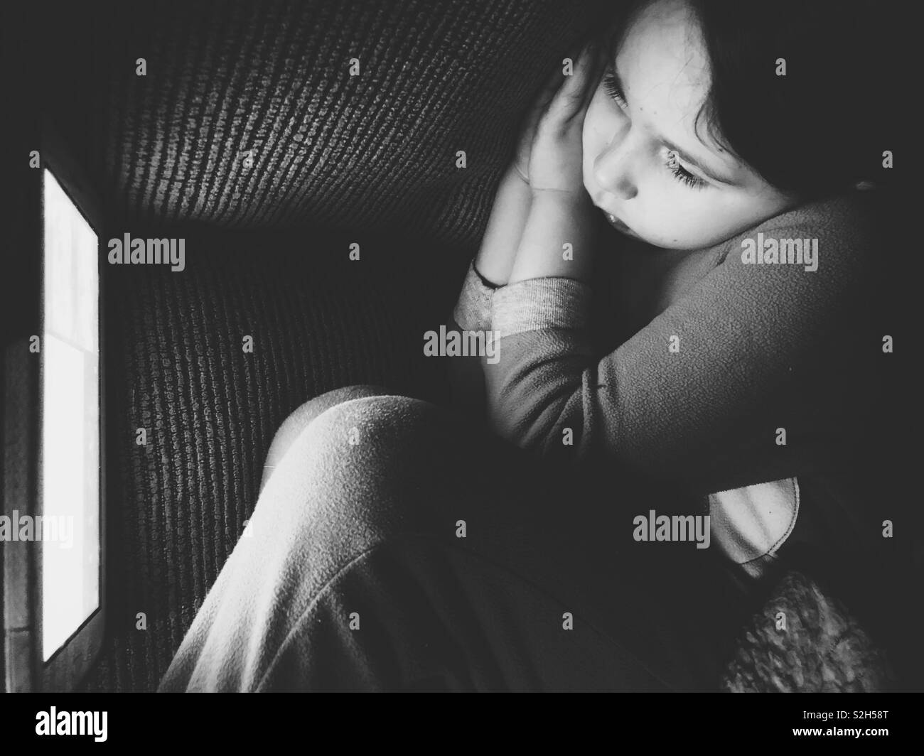 Un giovane bambino guardando un tablet con un annoiato, sleepy espressione nel buio Foto Stock