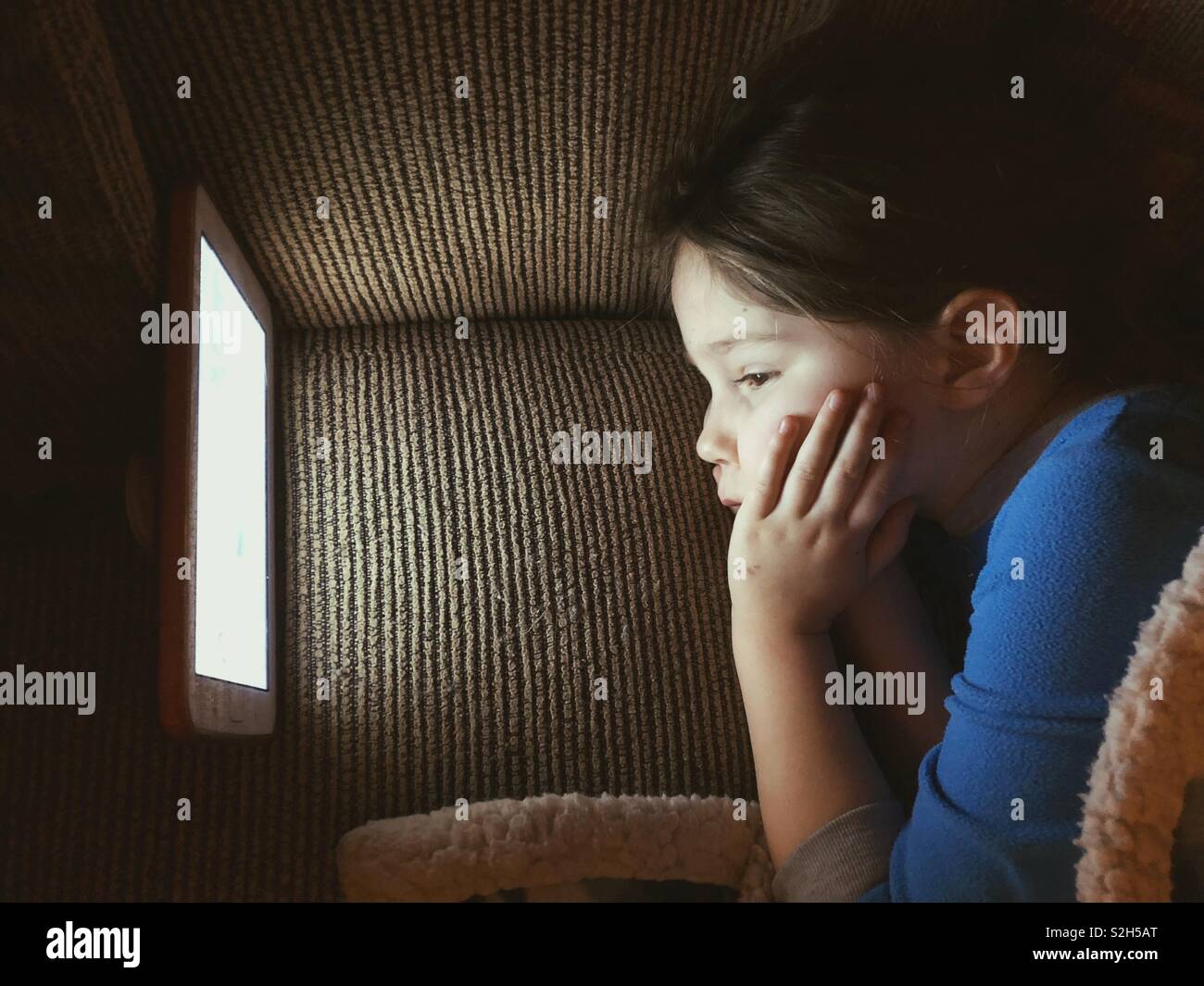 Un giovane bambino guardando lo schermo della compressa nel buio Foto Stock