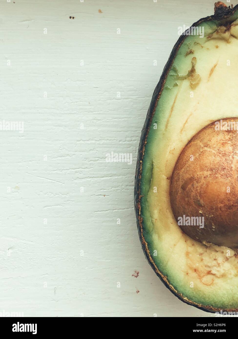 La metà di un molto mature metà di avocado con pit dipinte su sfondo bianco Foto Stock