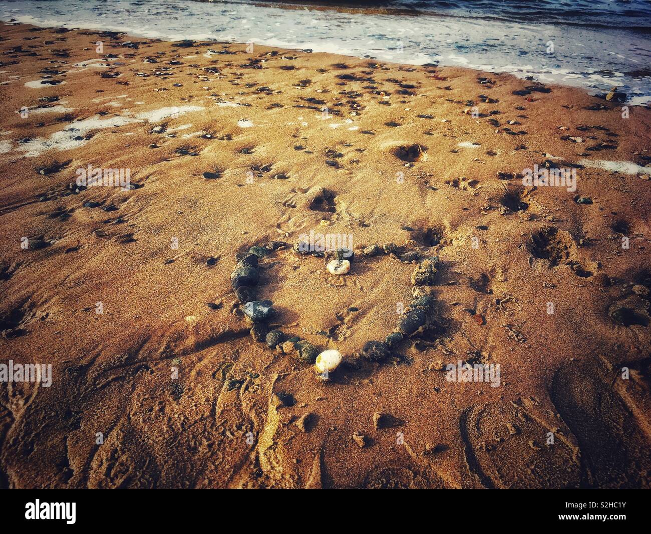 Un cuore di ciottoli su una spiaggia Foto Stock