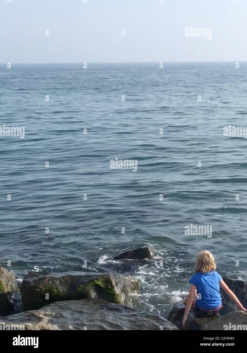 Bambino che guarda al mare dal bordo d'acqua Foto Stock