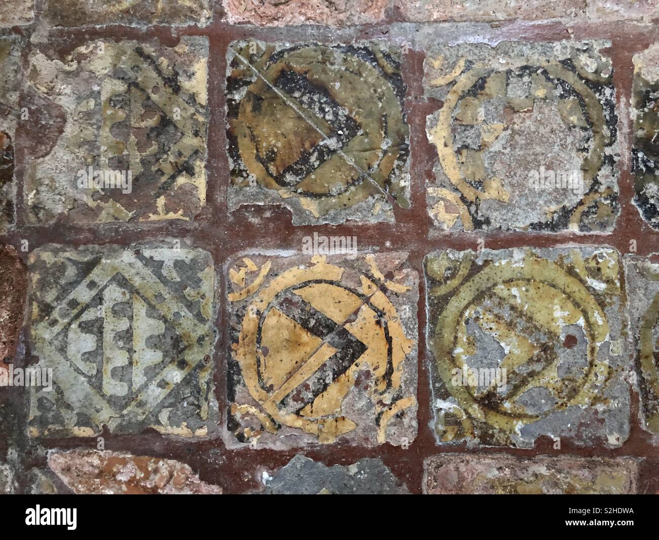 Encausto medievale di piastrelle con bel tempo colori sbiaditi e chevron, a corona foliate e disegni. Foto Stock