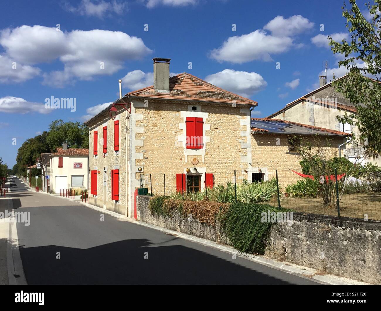 Rustico della casa francese nel villaggio di Bors, in Charente, dove dipinte di rosso persiane splendidamente a contrasto con il blu intenso del cielo. - Immagine stock catturata con smartphone Rustico della casa francese nel villaggio di Bors, in Charente, dove dipinte di rosso persiane splendidamente a contrasto con il blu intenso del cielo. - Immagine stock catturata con smartphone
