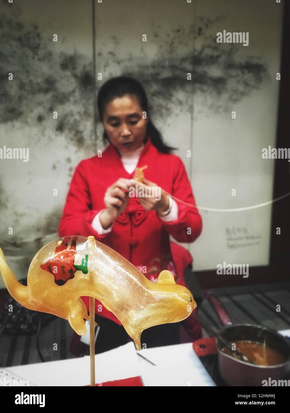Signora cinese fare una caramella a caldo di zucchero fuso in forma animale. Foto Stock