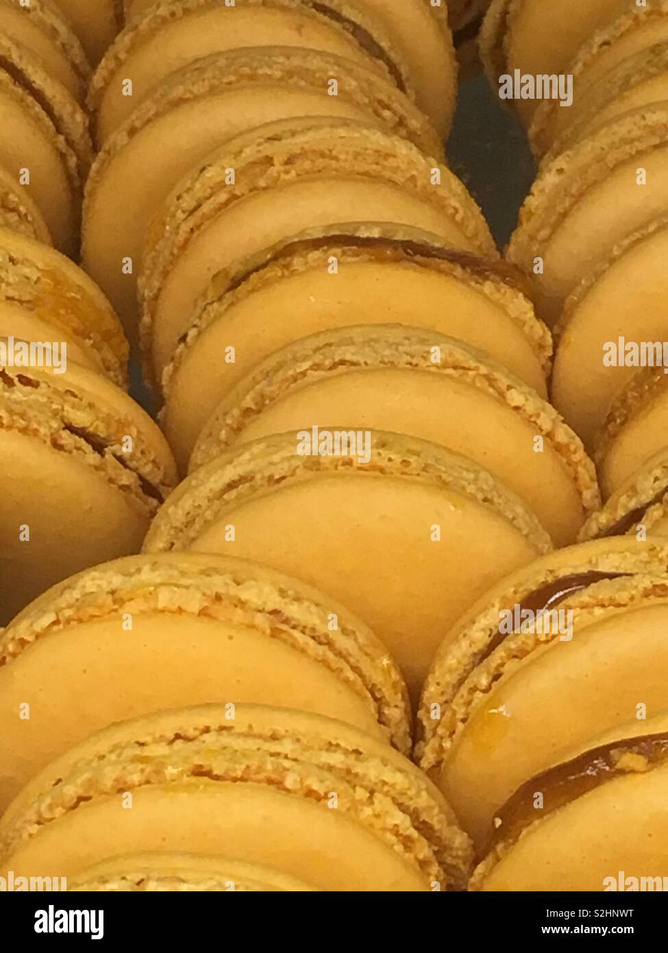 Delizioso francese giallo arancione macaron cookies impilati in una piastra come un croccante e dessert. Foto Stock