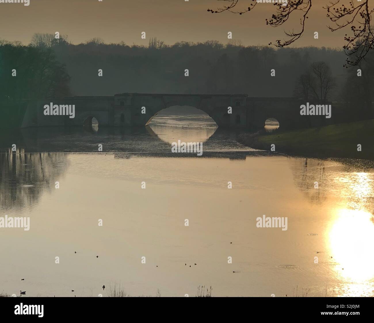 Il Grand Bridge, a Blenheim Palace, costruito da John Vanbrugh, tra il 1708 e il 1710, ed è considerata una delle più belle viste in Inghilterra, mostrato al tramonto con la mellow e riflessioni nebuloso nei laghi. Foto Stock