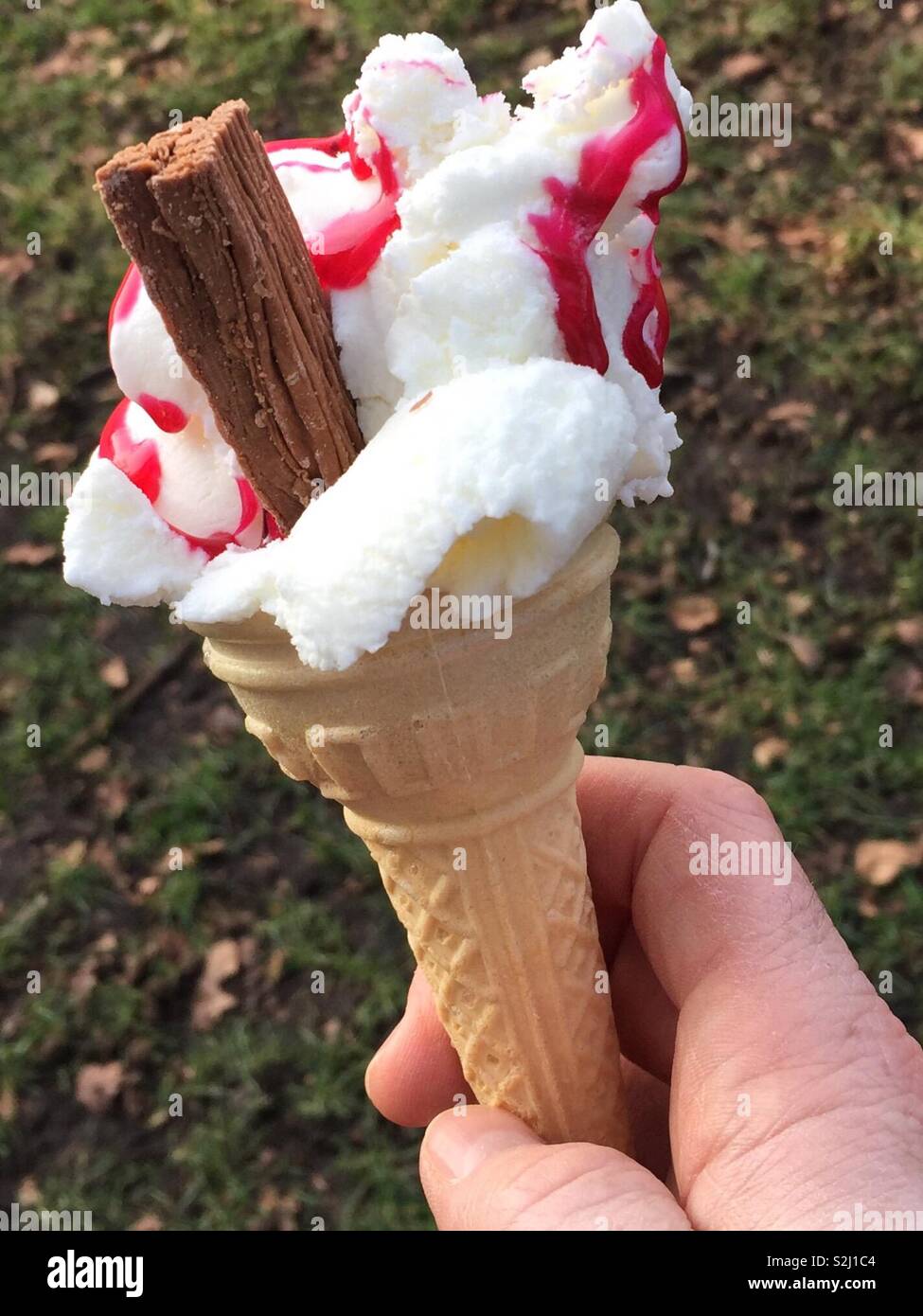 Cono gelato con scoop di deliziosi gelati, scaglie di cioccolato e lampone salsa di fragole. 99 Foto Stock