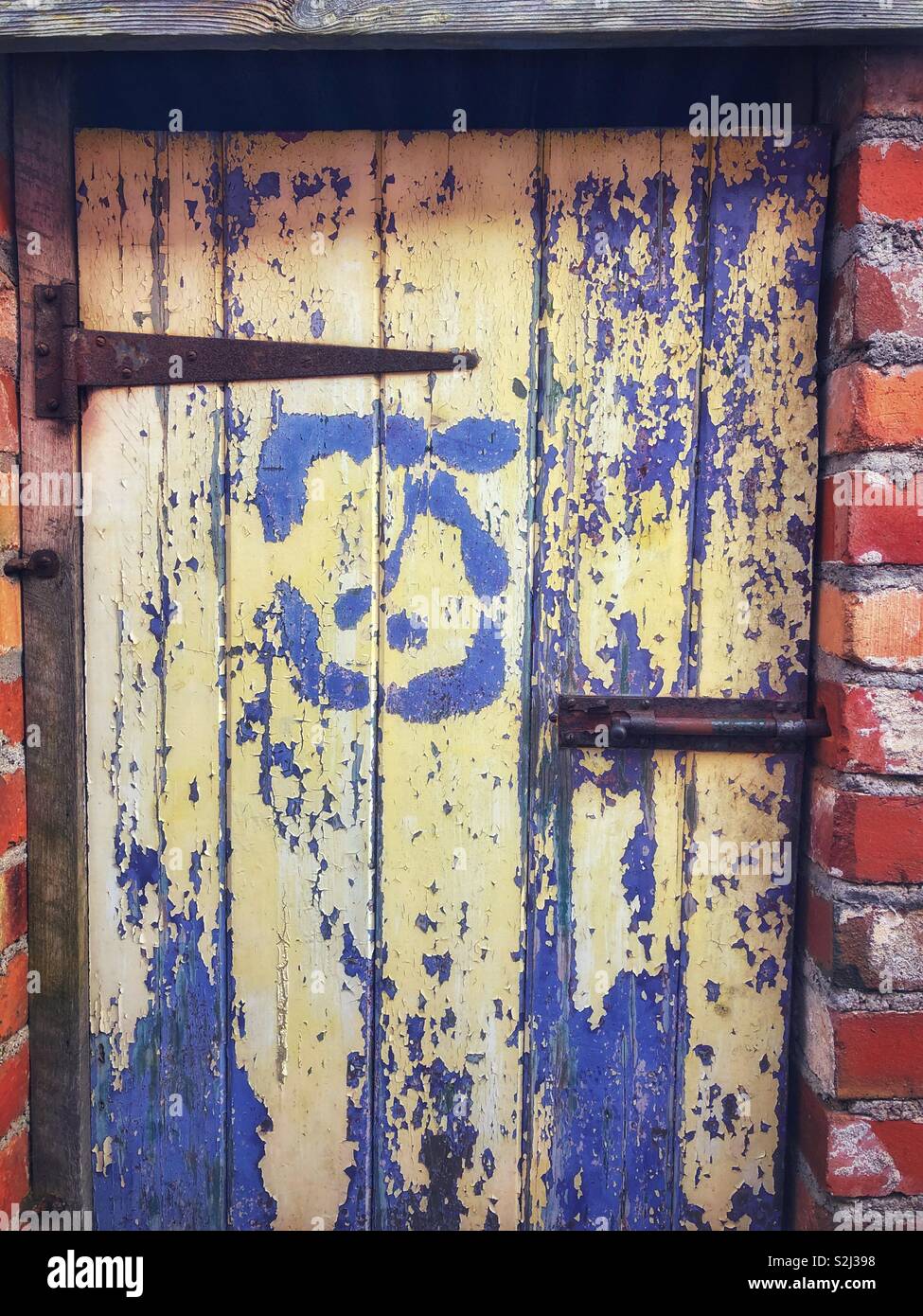 Vecchio sfald vernice su una toilette esterna porta. Foto Stock