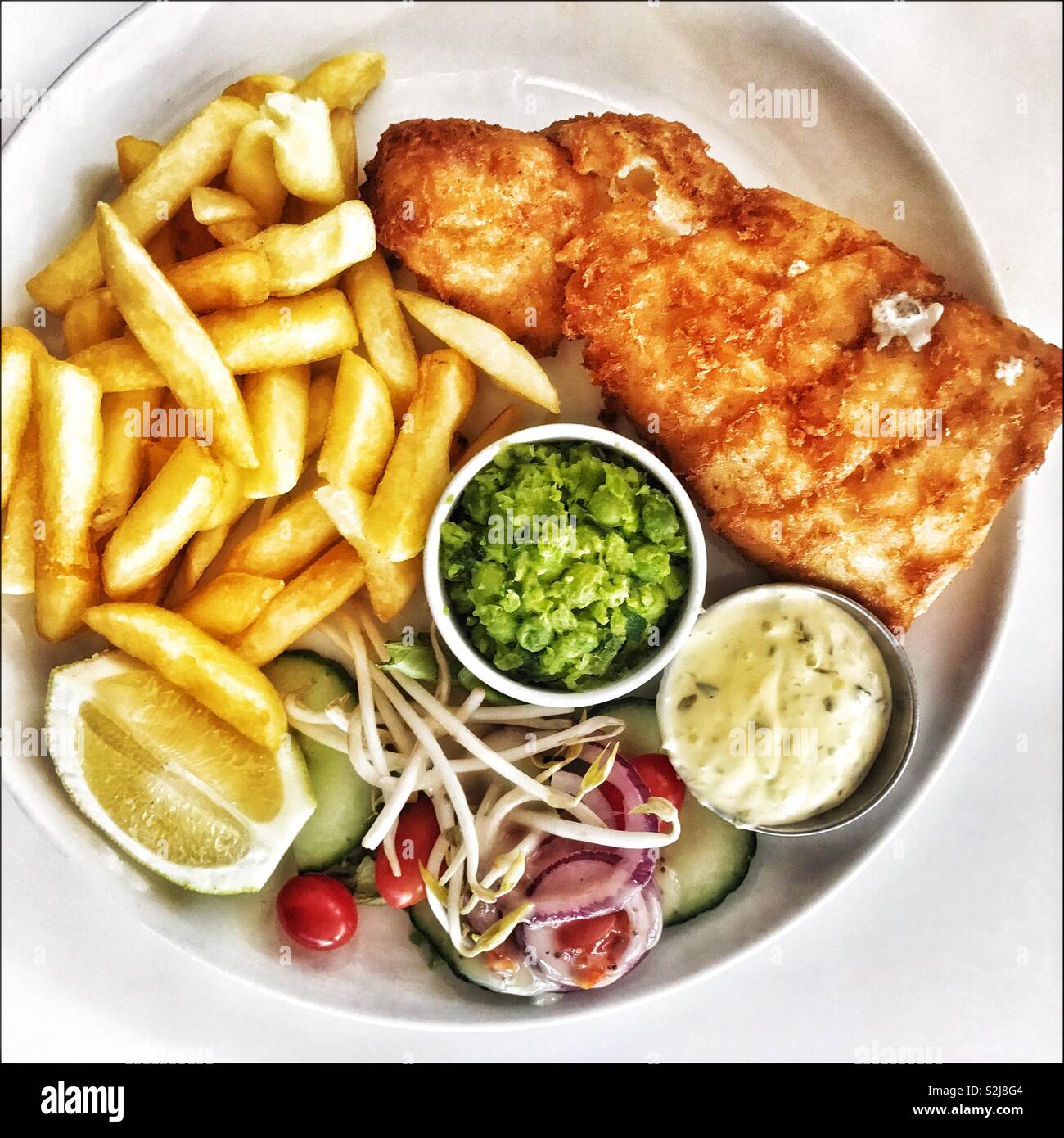 Pesce e patatine con fiacco di piselli e insalata di contorno. Foto Stock
