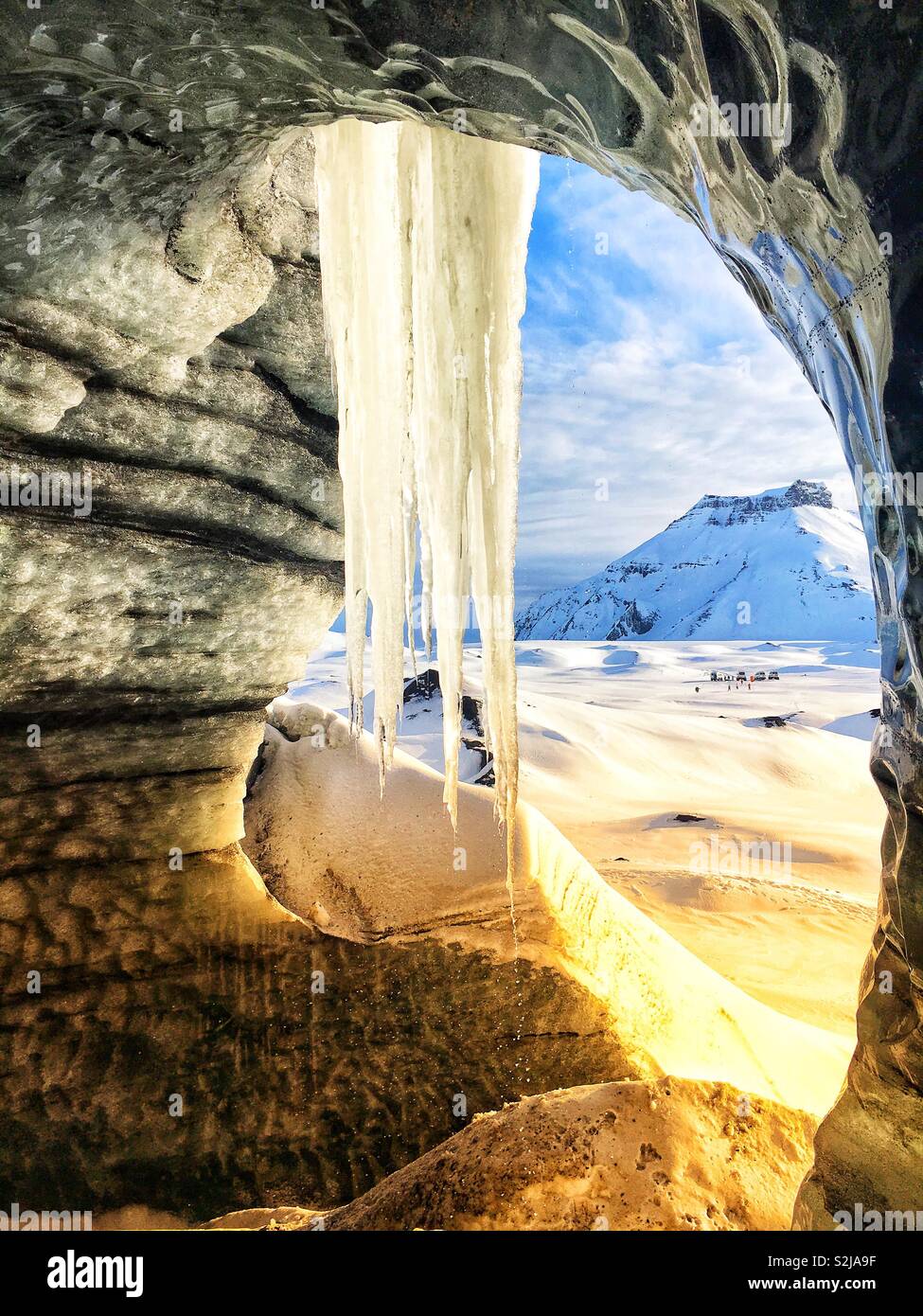 Ghiacciaio Katla caverna di ghiaccio nei pressi di Vik, Islanda che mostra un grande ghiacciolo nee l'ingresso della grotta a guardare i monti vicini. Foto Stock