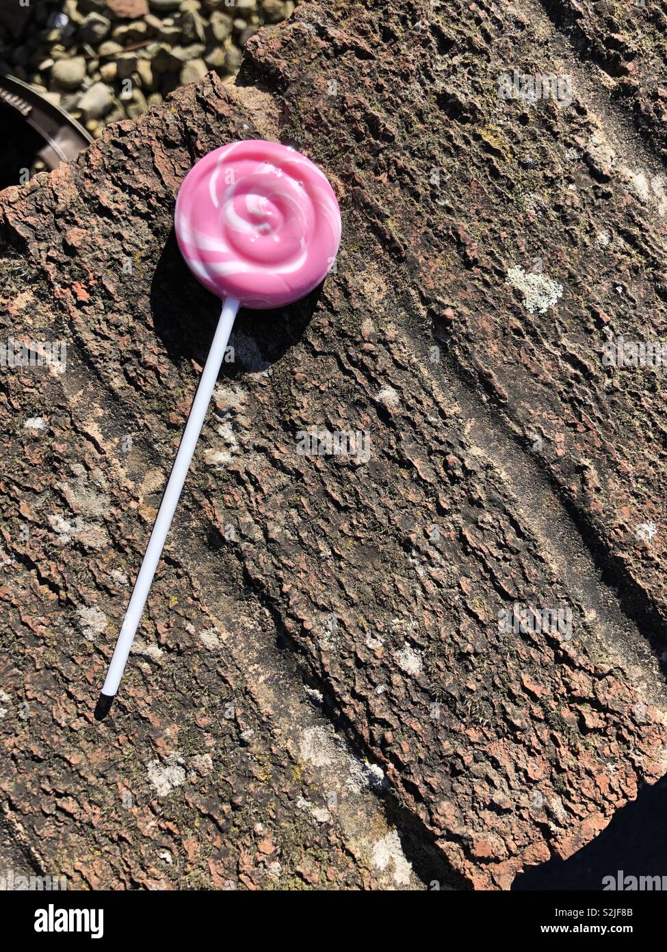 Rosa candy lollipop a sinistra sulla sommità di un muro di mattoni Foto Stock