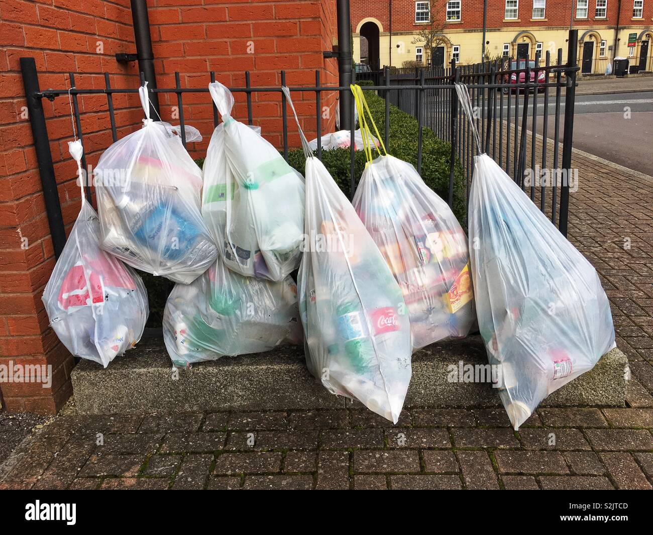 Sette grandi bianco sacchetti di plastica della spazzatura appesi sulle ringhiere, in attesa di raccolta in un moderno complesso residenziale. Foto Stock