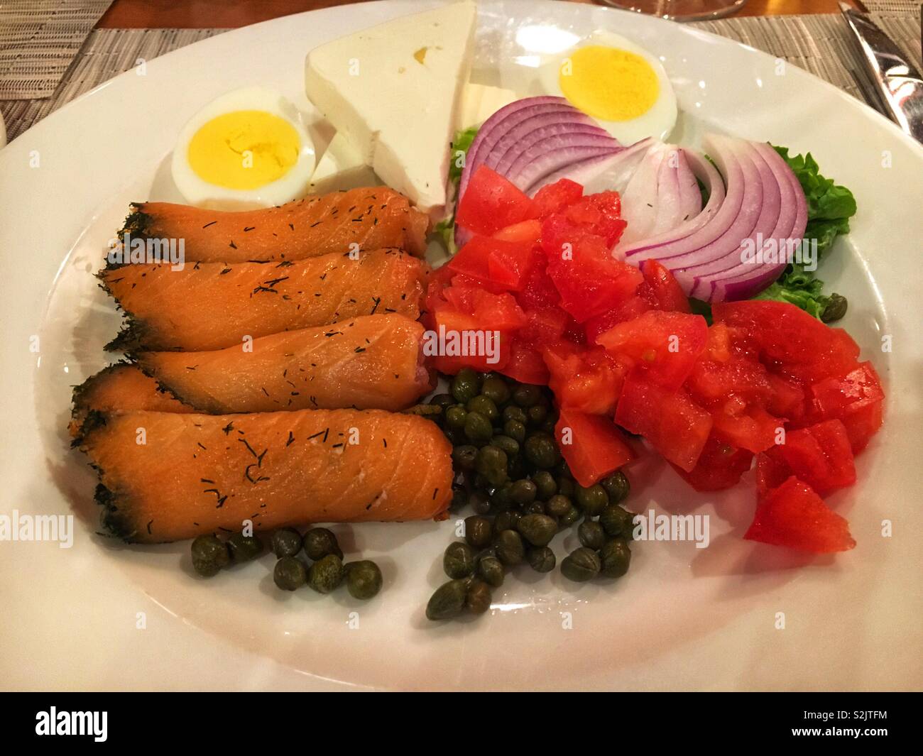 Deliziosa acquolina in bocca il salmone affumicato lox di piastra con cipolle rosse, i pomodori a dadini, capperi, e perfettamente un uovo sodo tagliato a metà. - Immagine stock catturata con smartphone