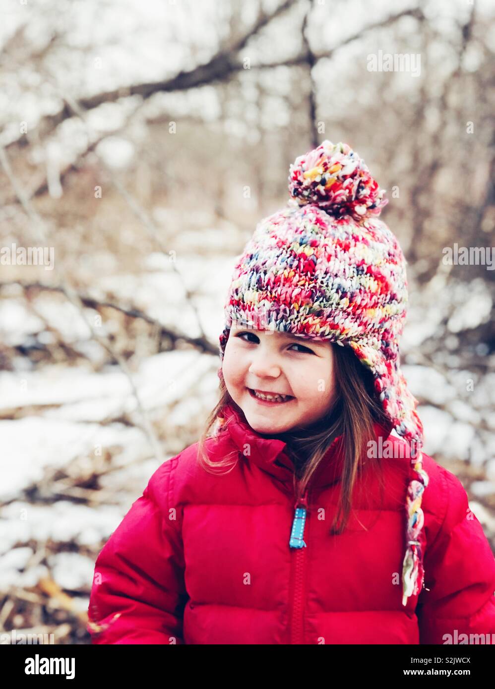 Ritratto di sorridere 3 anno vecchia ragazza indossando Cappello invernale e rivestire in una foresta - Immagine stock catturata con smartphone