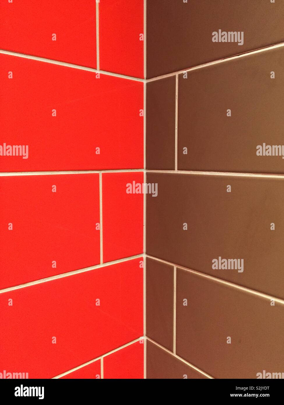 E sfondo astratto di un colorato di rosso e marrone parete piastrellata con prospettiva in diminuzione in un angolo con lo spazio di copia Foto Stock