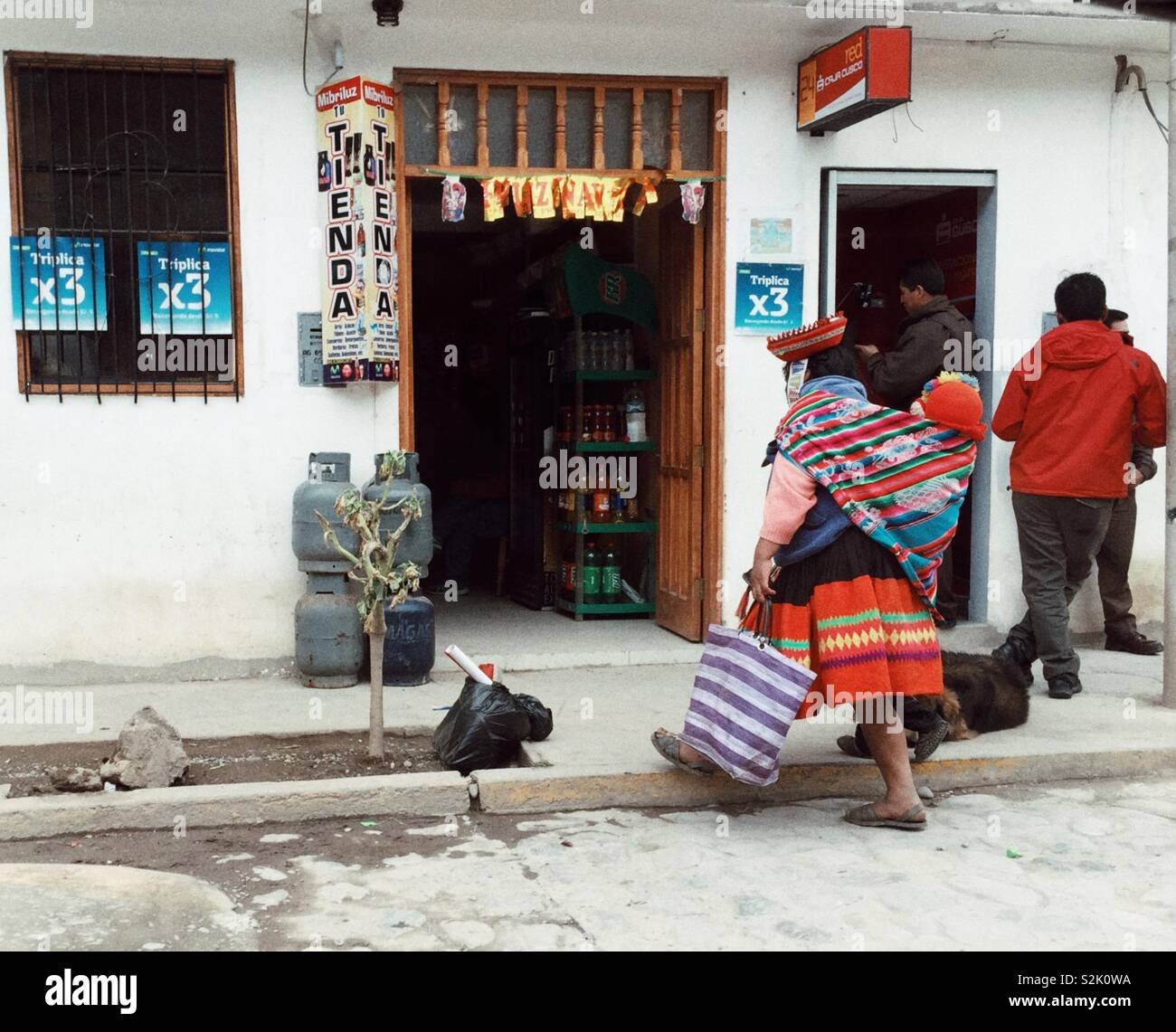 Indigeni Donna Peruviana con il bambino sulla schiena di passeggiate in un locale di tienda Foto Stock