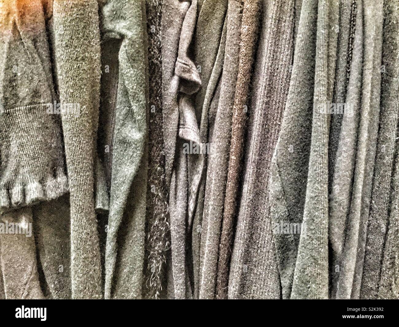 Vista laterale di molti di moda tenui tinte grigio vestiti appesi a un rack di abbigliamento. Foto Stock