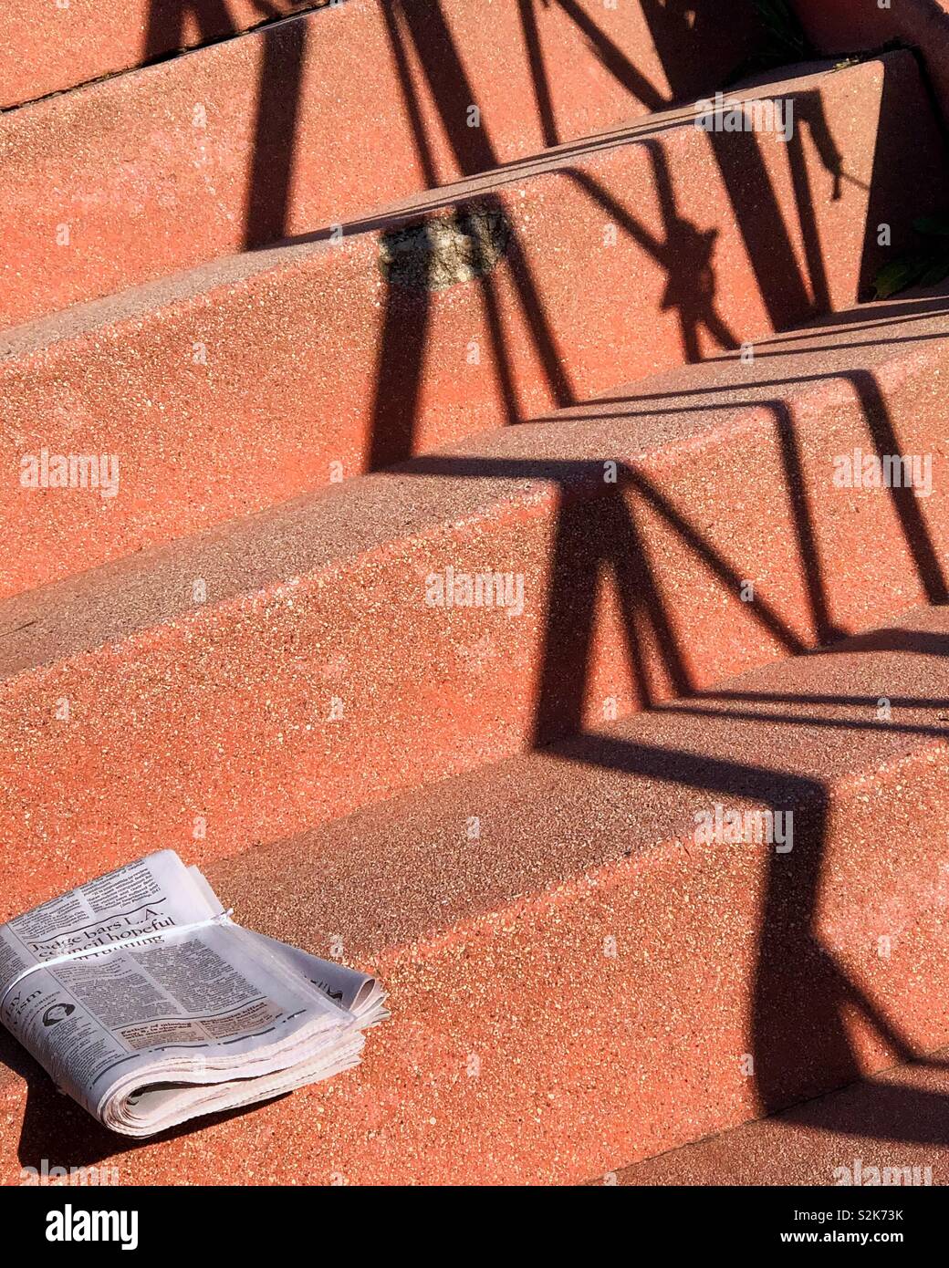 Carta di mattina seduti sui gradini di fronte alla luce del sole. Foto Stock