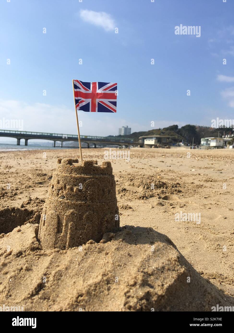 Sandcastle e Union Jack flag sotto un cielo blu Foto Stock