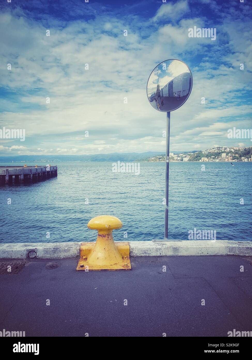 Un bollard giallo e uno specchio vicino al mare Foto Stock