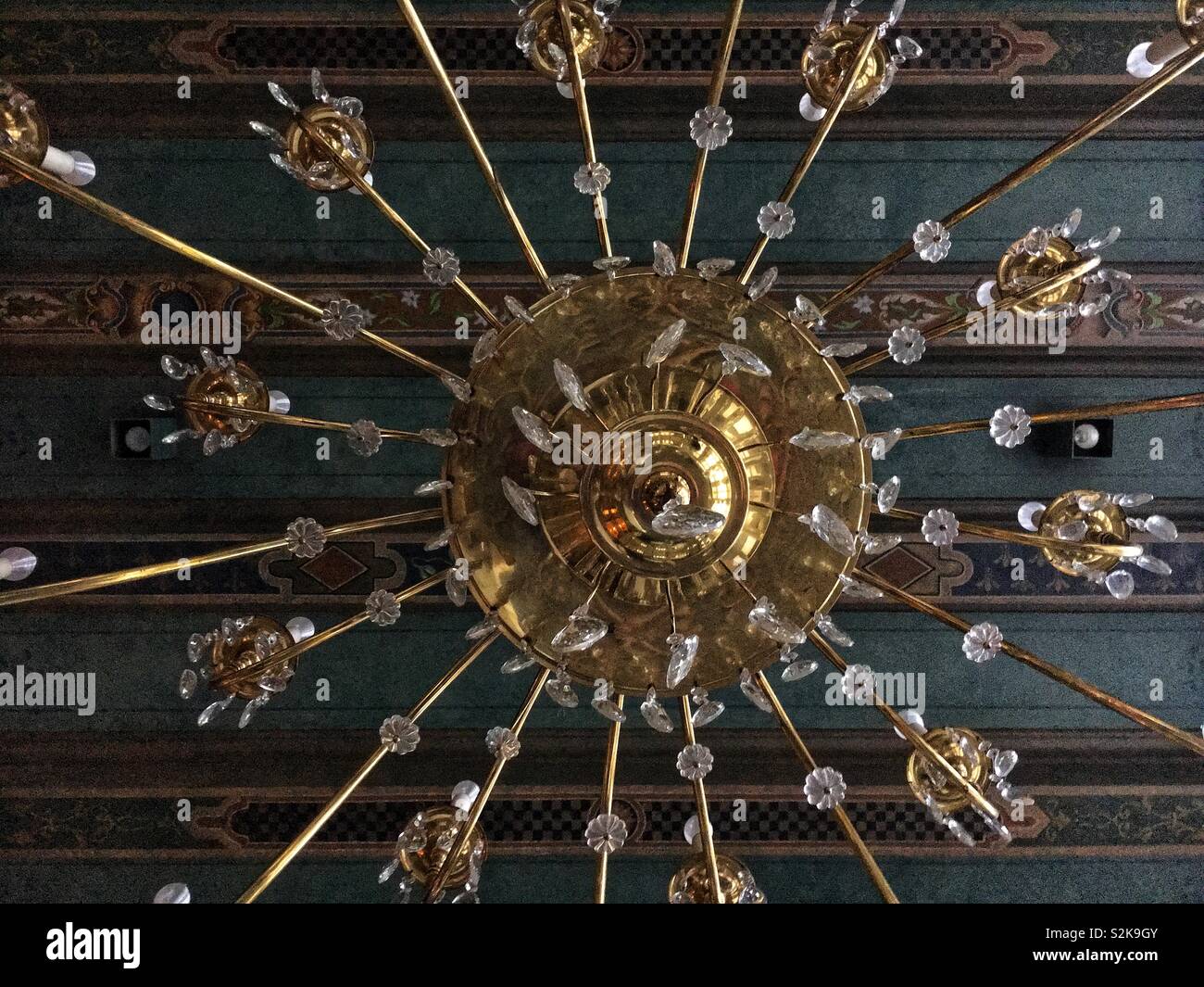 Molto elegante e di elaborare un lampadario appeso dal verde ornato soffitto a travi. Foto Stock