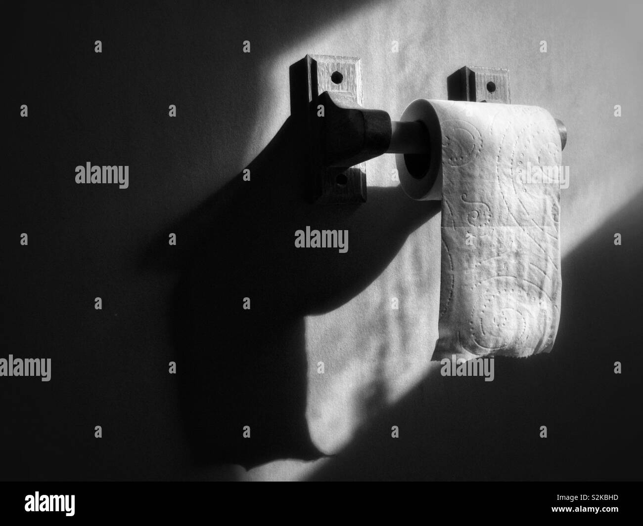 Rotolo di carta igienica su supporto in legno in bianco e nero Foto Stock