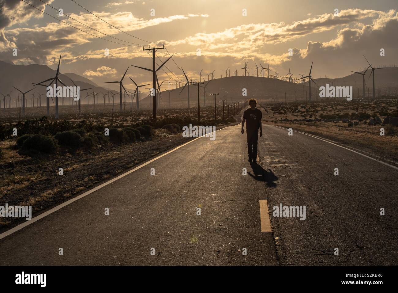Mio figlio a passeggio tra valle di Coachella mulini a vento vicino a Palm Springs al golden ora. - Immagine stock catturata con smartphone