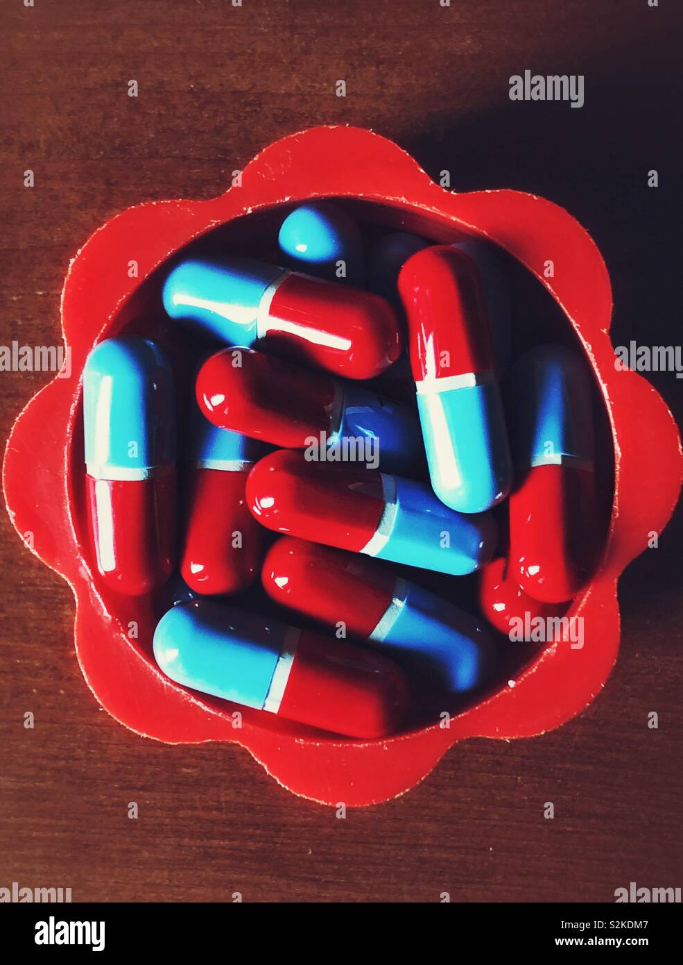 Rosso e blu pillole in un rosso contenitore in plastica - Immagine stock catturata con smartphone