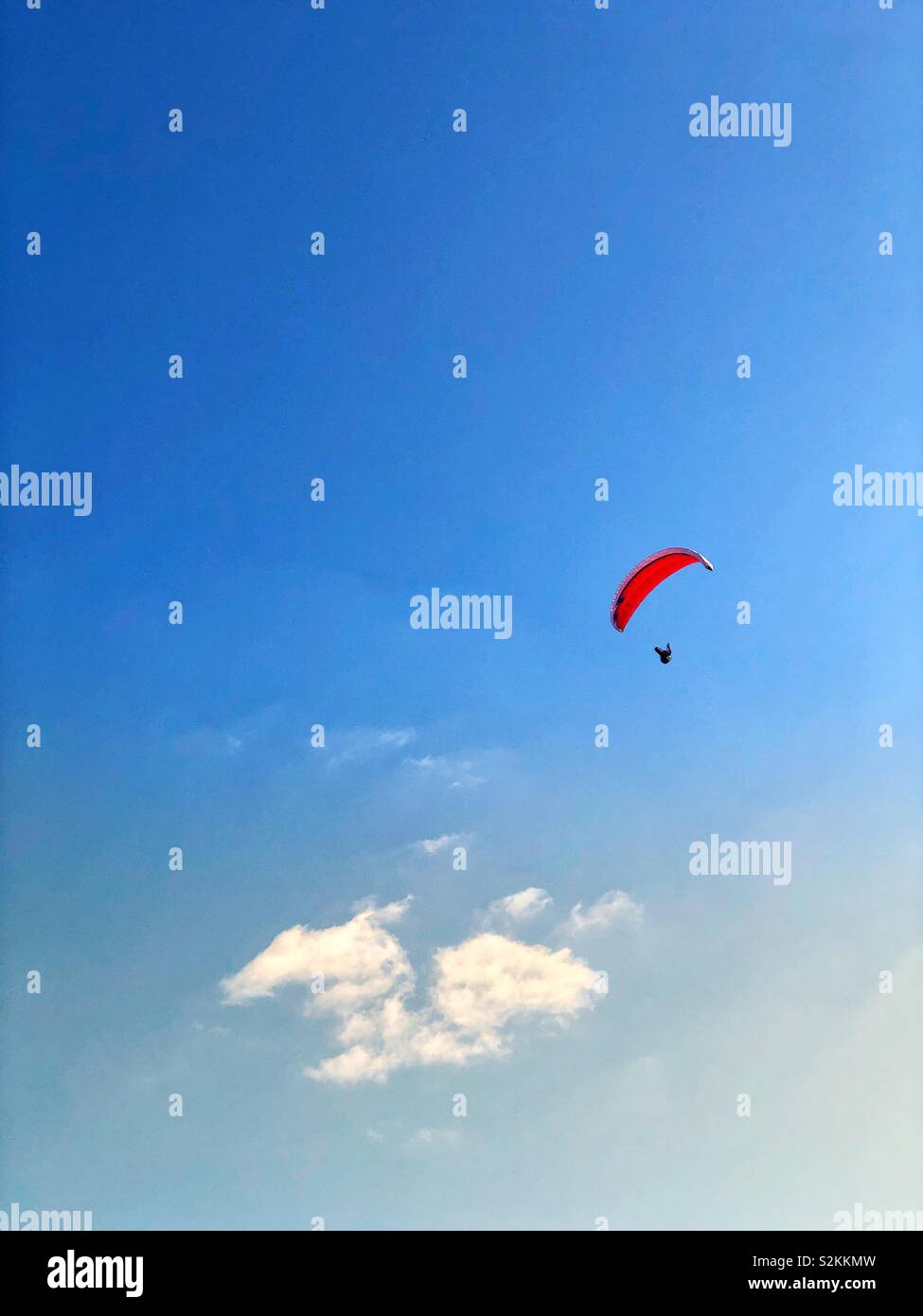 Parapendio con baldacchino rosso passando sopra una nuvola Foto Stock