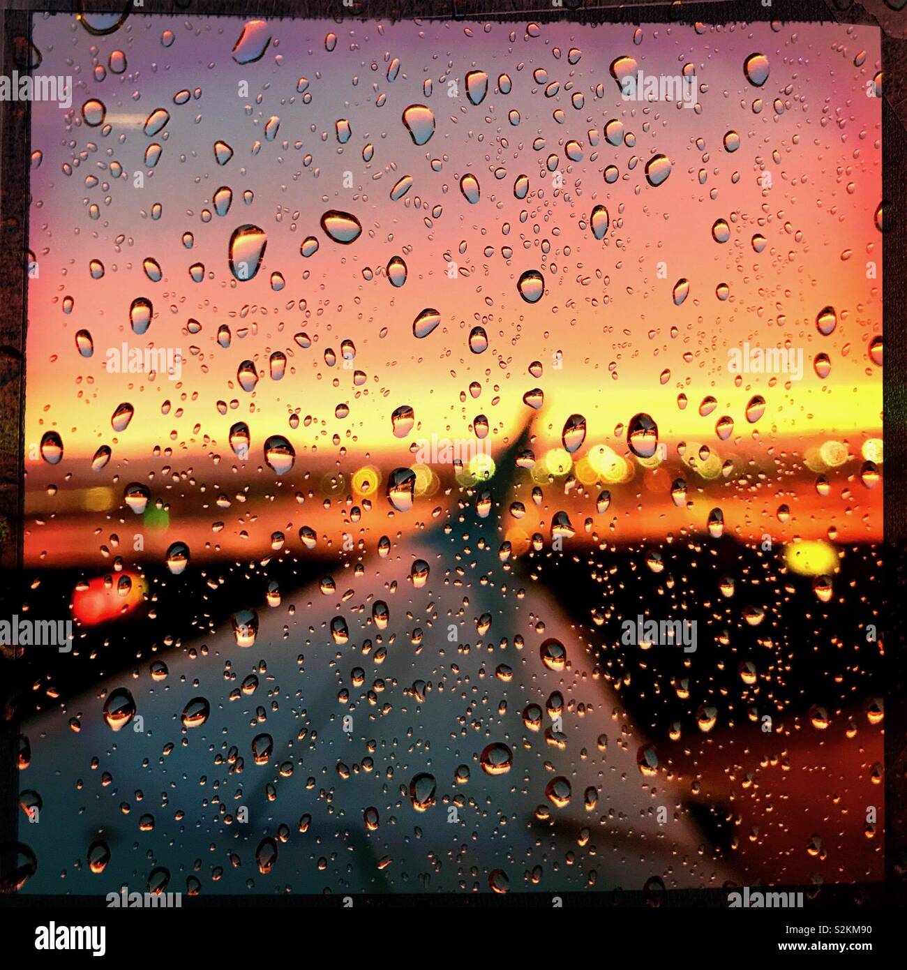 Tramonto sfocata attraverso gocce di pioggia sulla finestra di aeromobili Foto Stock