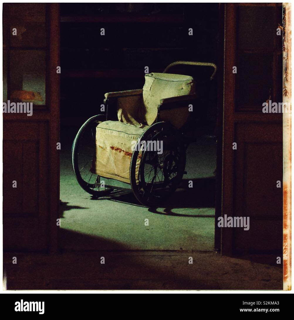 Sedia a rotelle Vintage nel buio della cantina Foto Stock