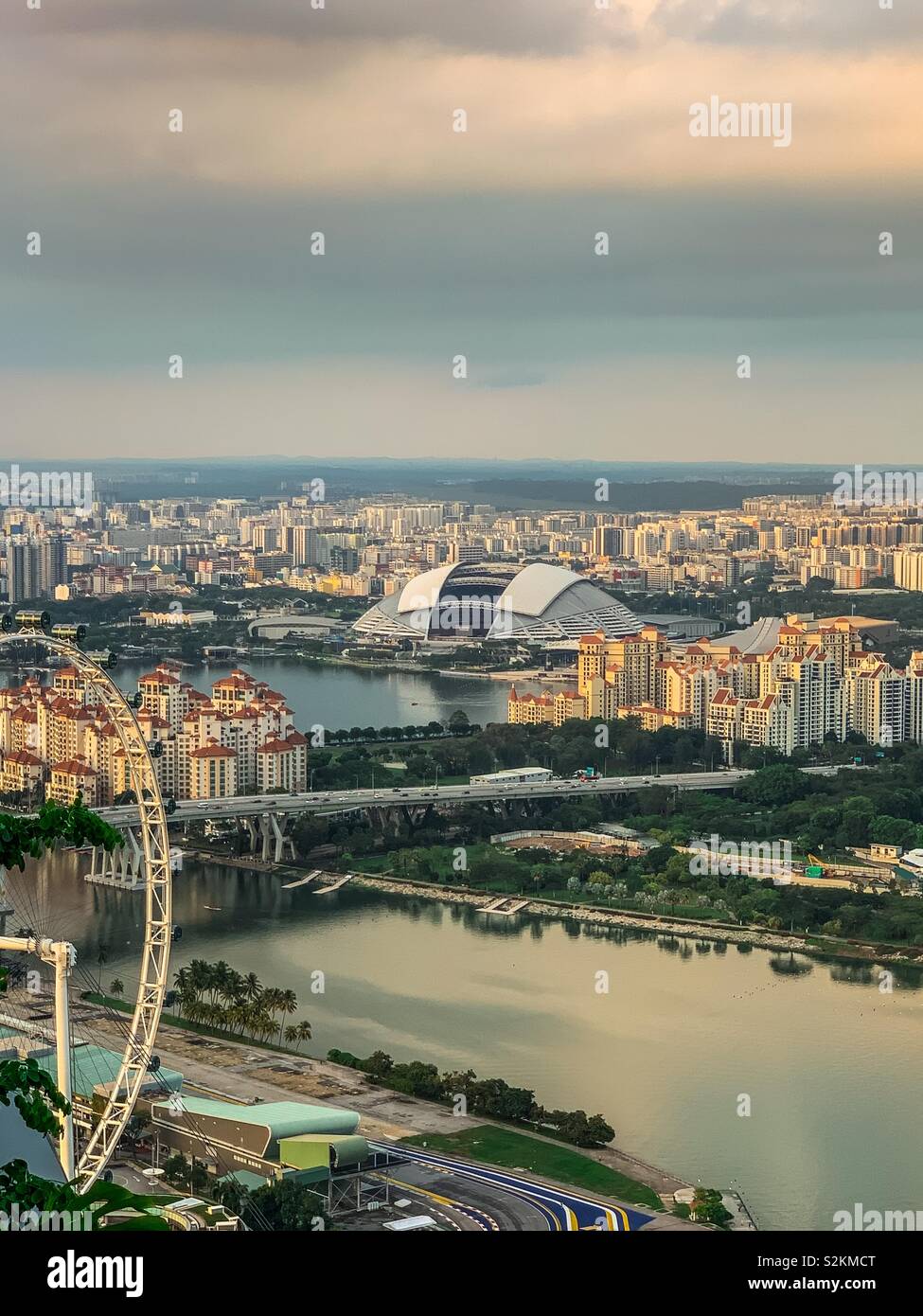 Singapore National Stadium circondato da edifici commerciali e residenziali e fiumi. Vista parziale del Singapore Flyer sulla destra. Foto Stock
