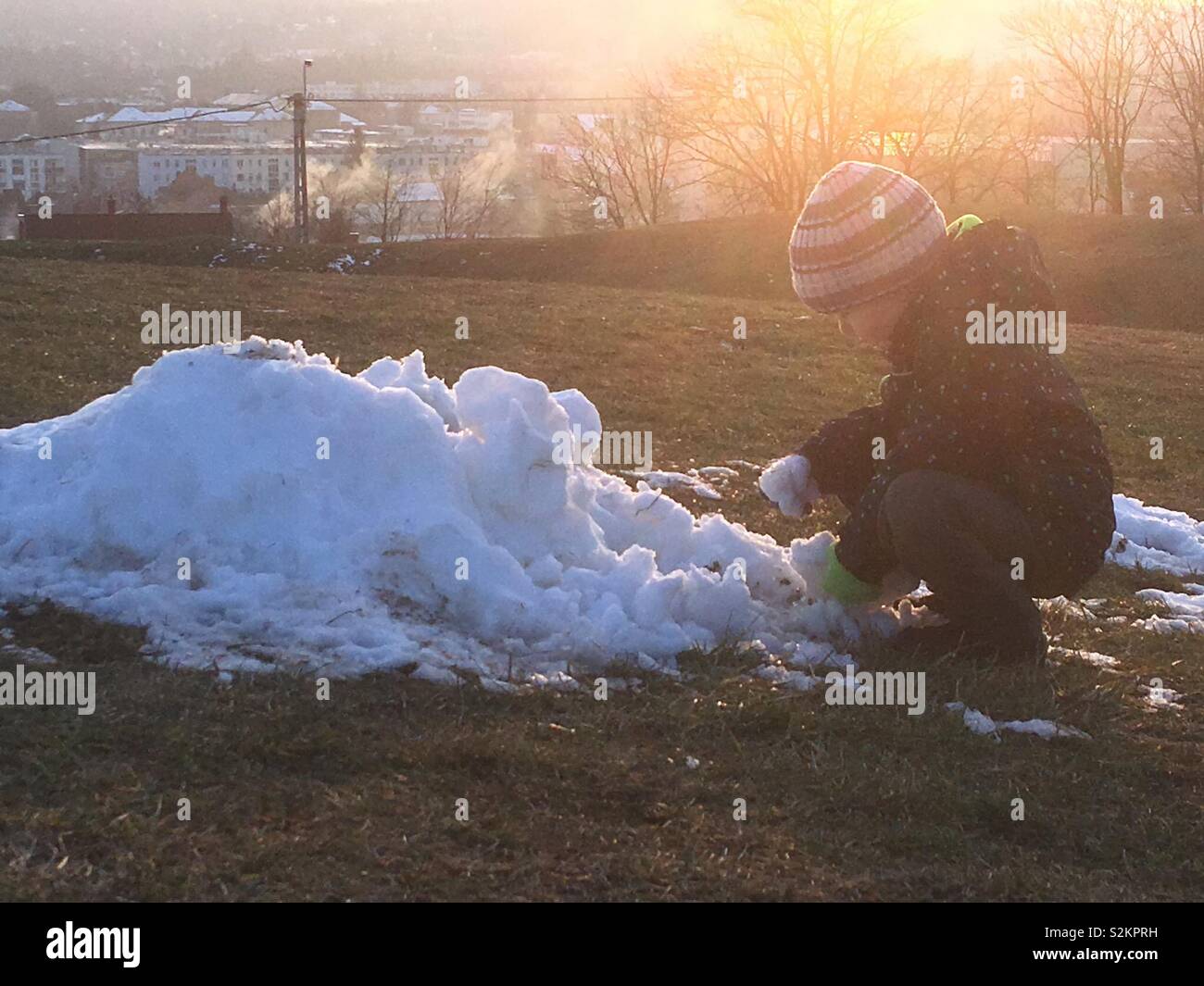 Ragazzo bambino che gioca con la neve in primavera - Immagine stock catturata con smartphone
