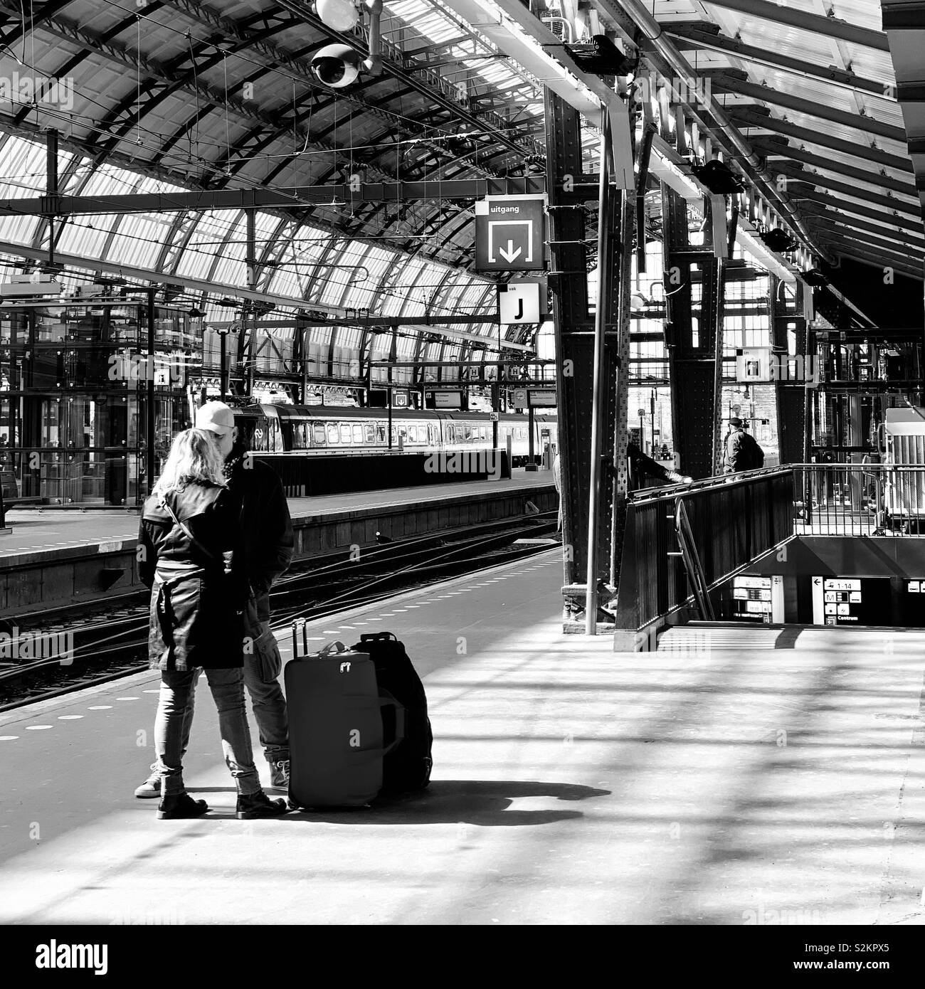 Amsterdam, Paesi Bassi - 12 Aprile 2019: una coppia in attesa di un treno in corrispondenza della piattaforma 15, stazione centrale. Foto Stock