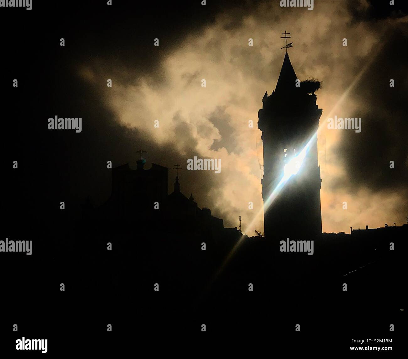 Il sole splende dopo una tempesta attraverso la torre campanaria della chiesa di Prado del Rey, Sierra de Cadice, Andalusia, Spagna Foto Stock