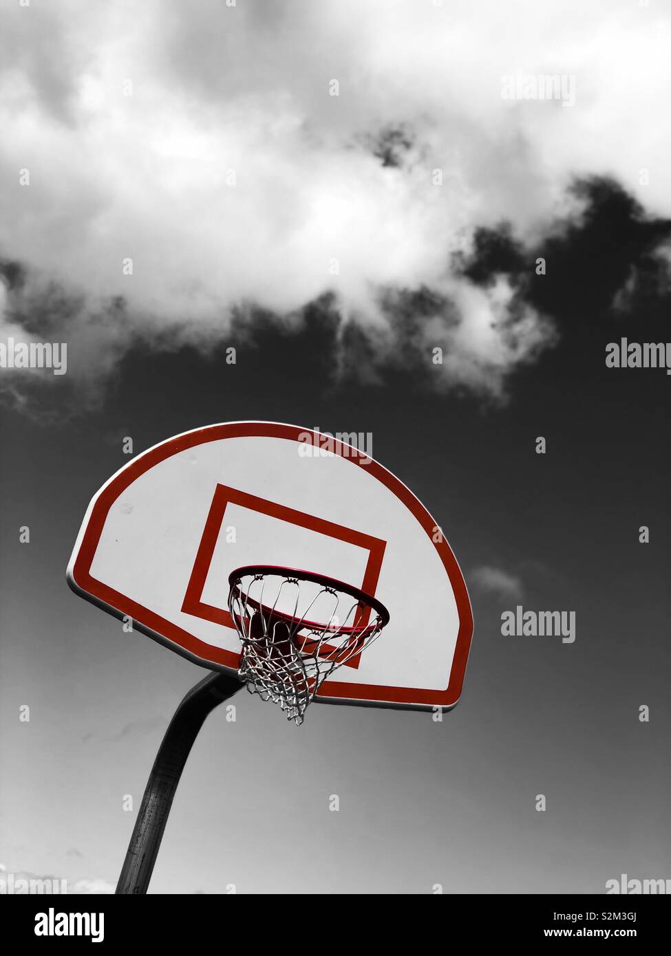 Un Basketball hoop contro un bianco e nero cielo molto nuvoloso Foto Stock