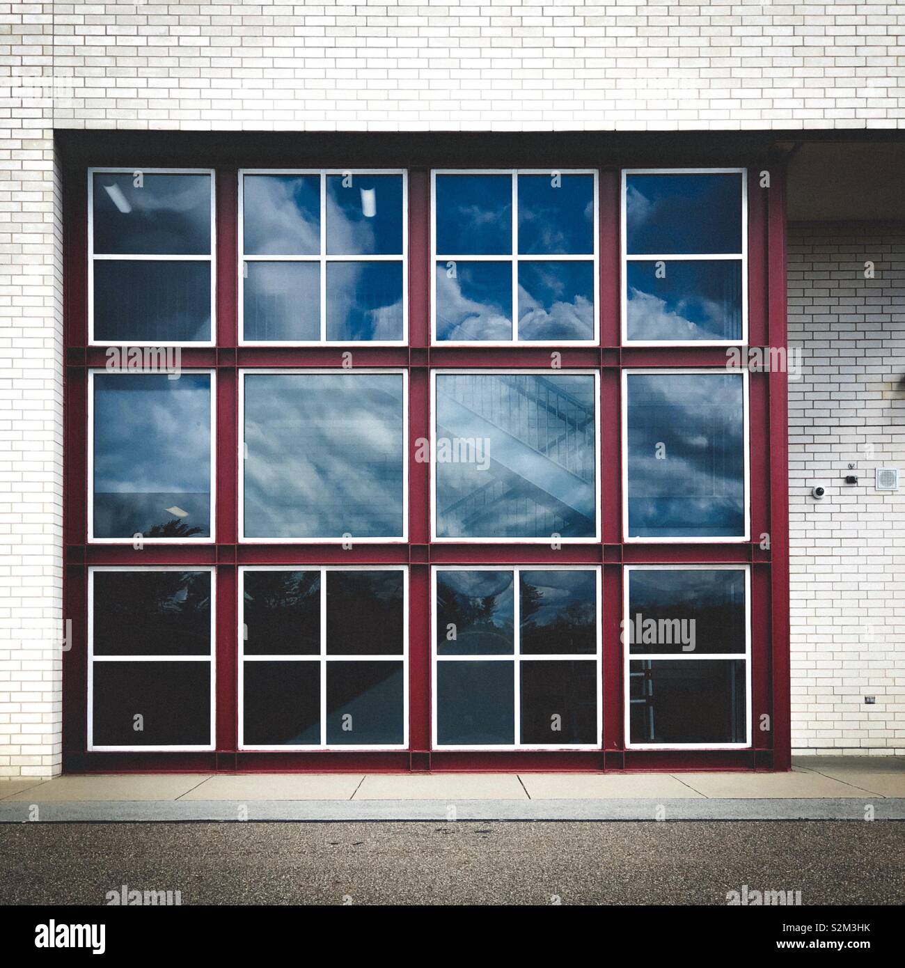 Finestre sulla facciata di un edificio di mattoni bianchi che riflette il cielo nuvoloso Foto Stock