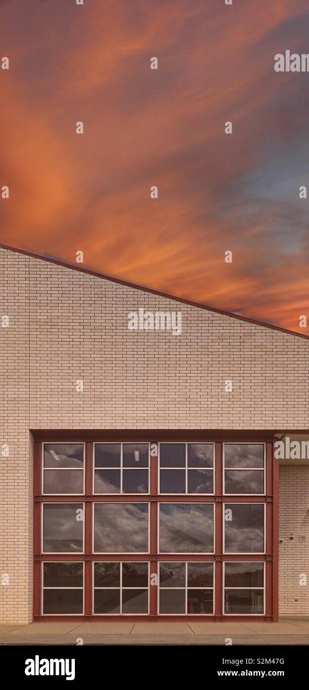 Un edificio con una finestra con molti vetri contro un arancione tramonto Cielo Foto Stock