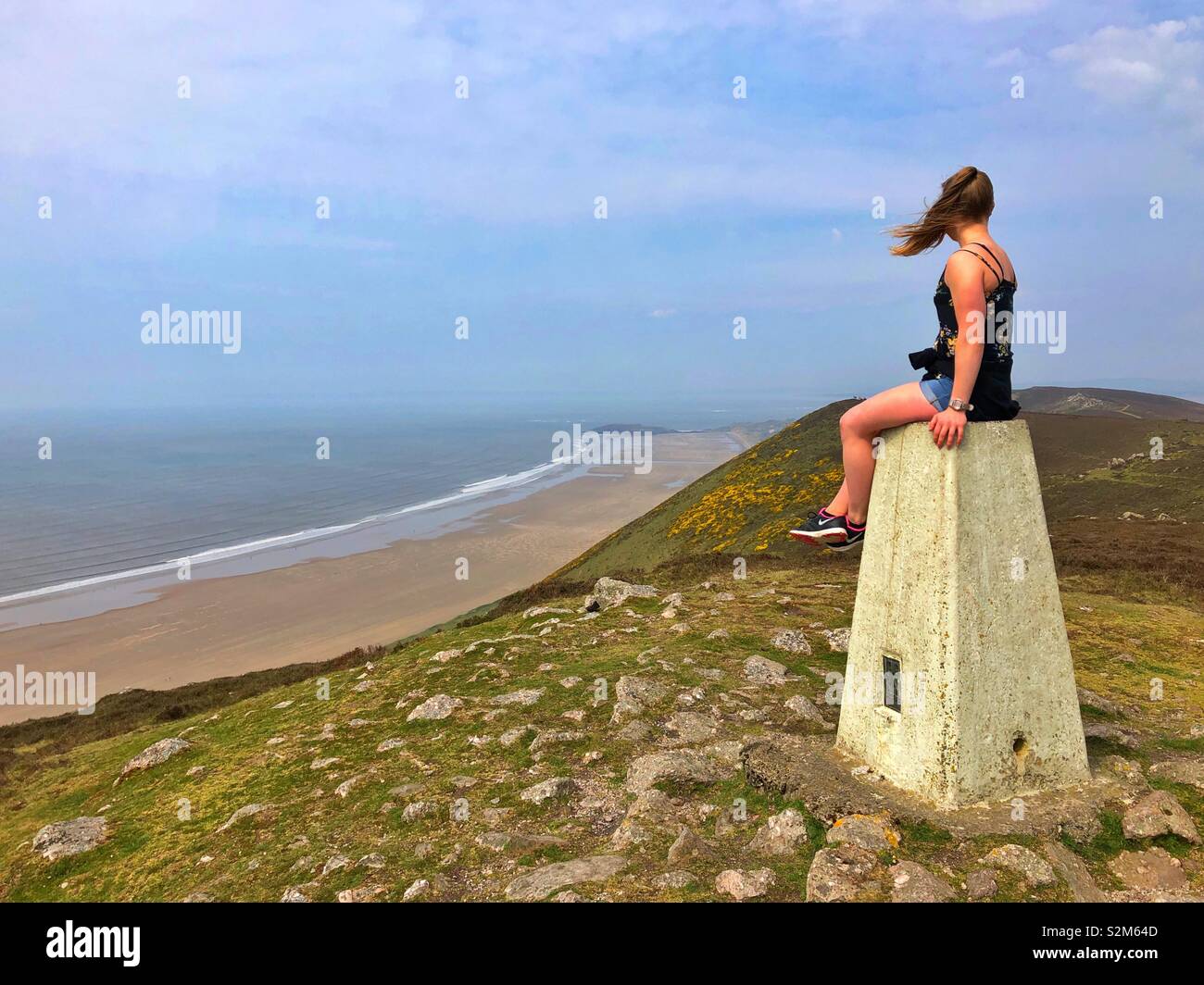 Giovane donna godendo la vista su Llangennith e Burry Holmes da Rhossili Downs. Foto Stock