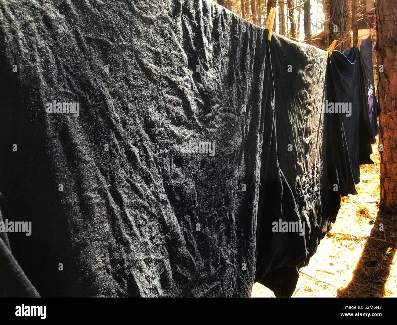 Goth servizio lavanderia in giornata- una fila di magliette nere appendere su uno stendibiancheria in una giornata di sole Foto Stock