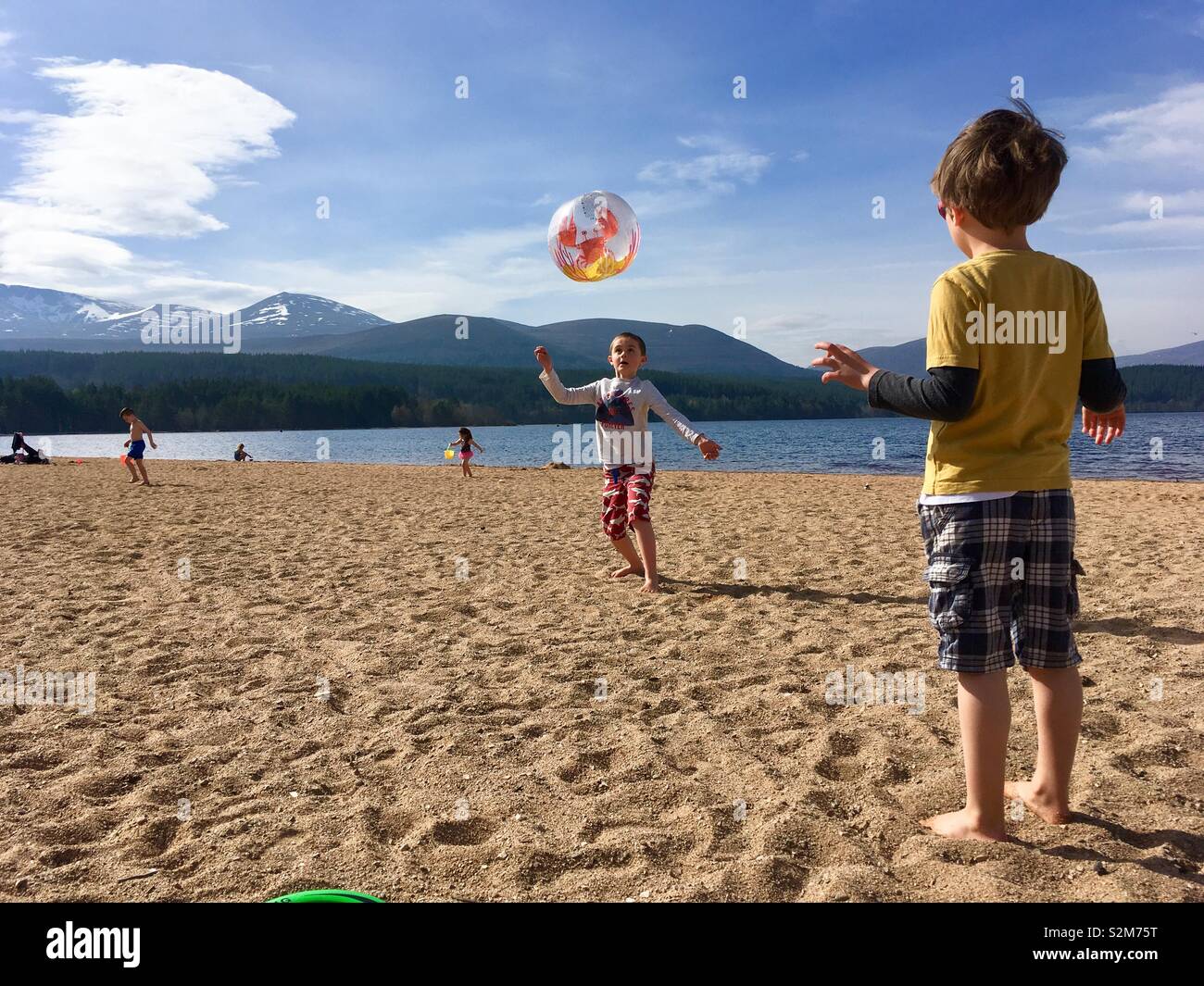 Ragazzi giocare con palla spiaggia sulla spiaggia accanto a Loch Foto Stock
